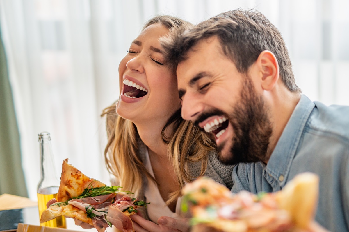 Two people laughing over pizza